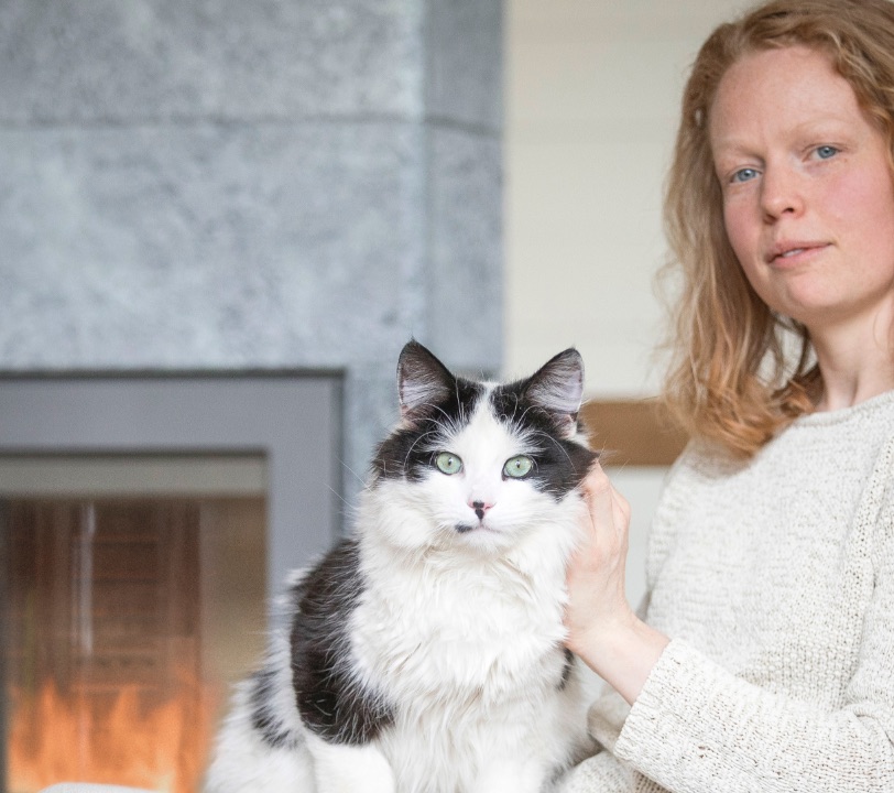 Vrouw met kat met op de achtergrond een speksteenkachel